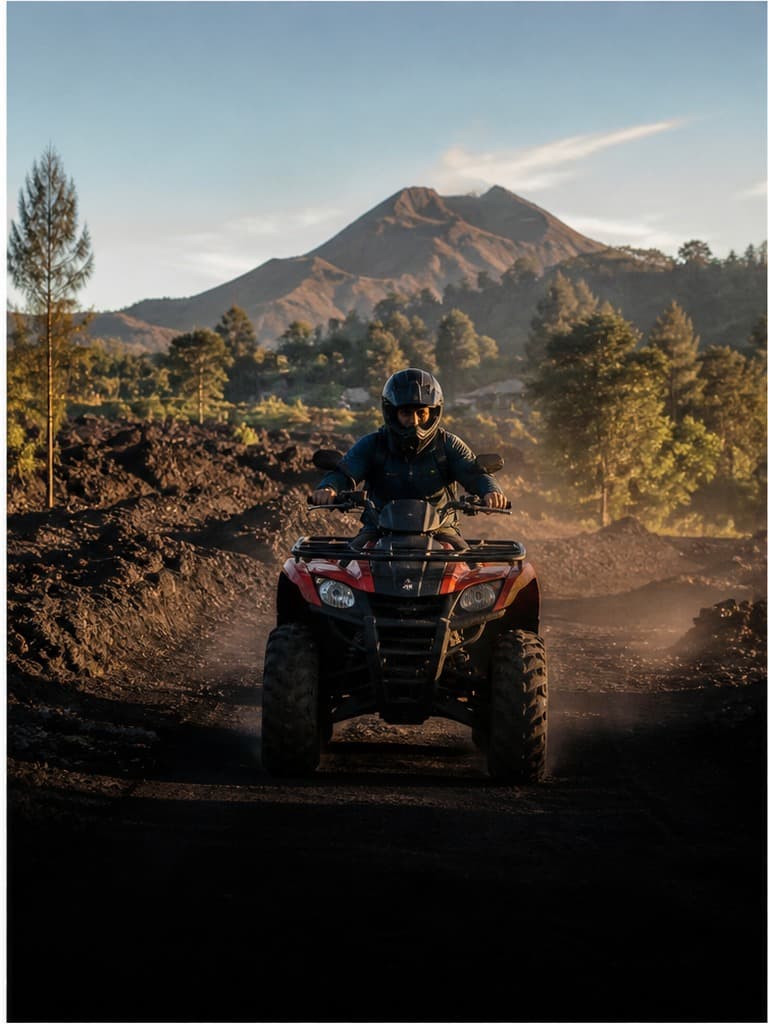 A helmeted rider on a quad bike crossing a volcanic dirt track near Mount Batur